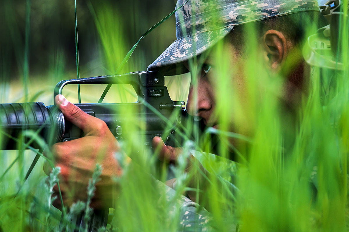 A U.S. Air Force Academy cadet takes cover, obscured by tall grass and foliage during Expeditionary Skills Training in Jacks Valley on June 28, 2019.