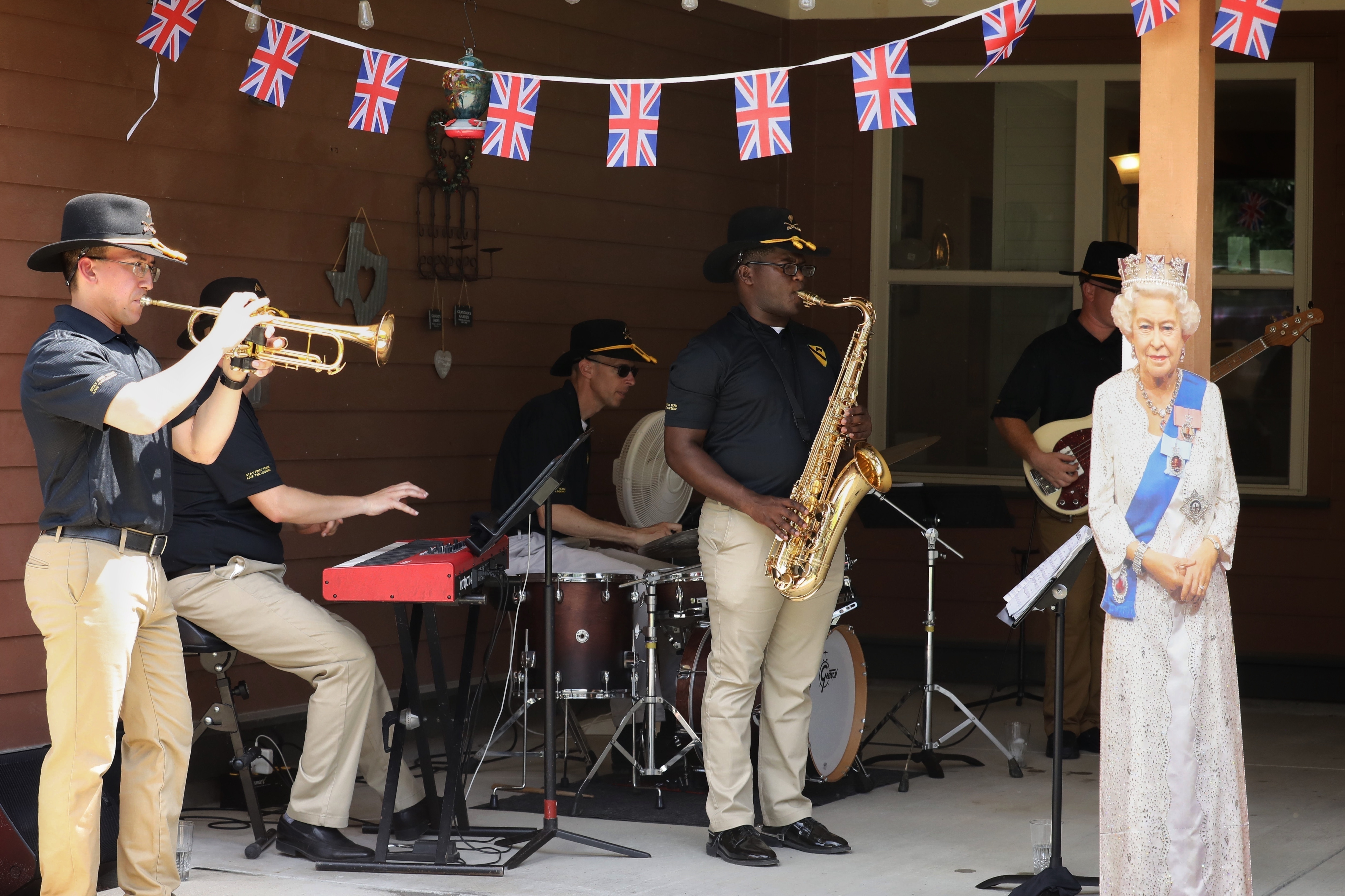 The 1st Cavalry Division Band performs during the Platinum Jubilee celebration for the Queen of England, Elizabeth II, at Fort Hood, Texas, Jun. 4, 2022, with a cardboard cutout of the queen.